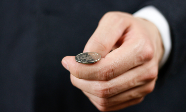 A close-up of a hand holding a coin 
Description automatically generated