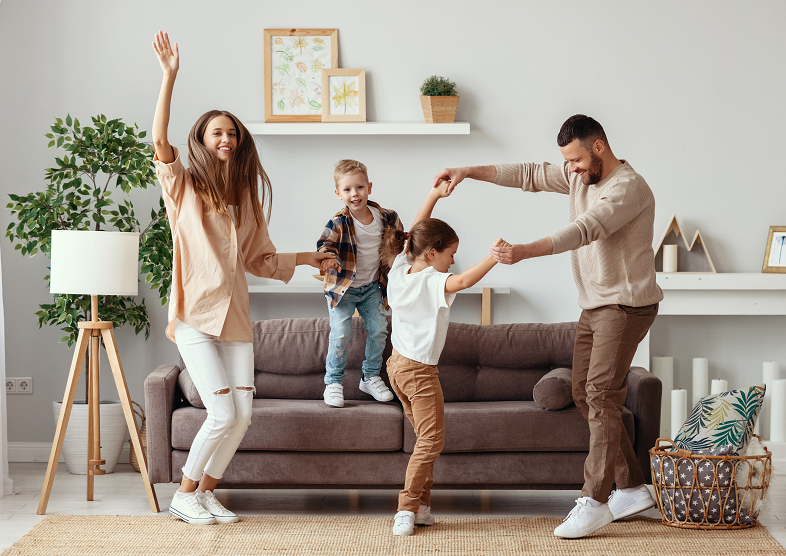 A family dancing in a living room 
Description automatically generated