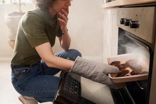 A person putting food in a tray

Description automatically generated