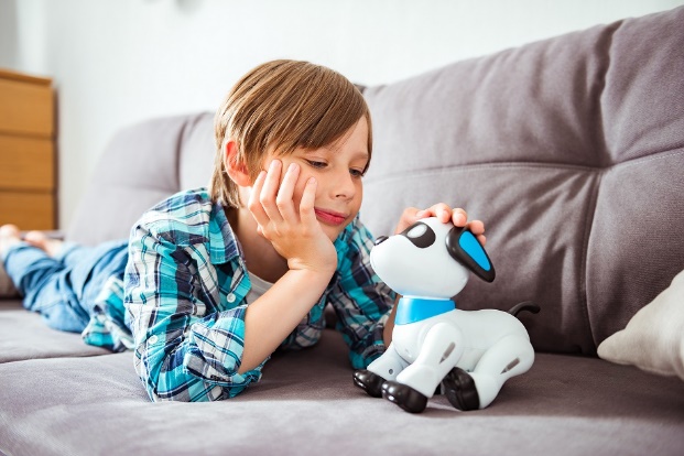 A child lying on a couch with a toy dog

Description automatically generated