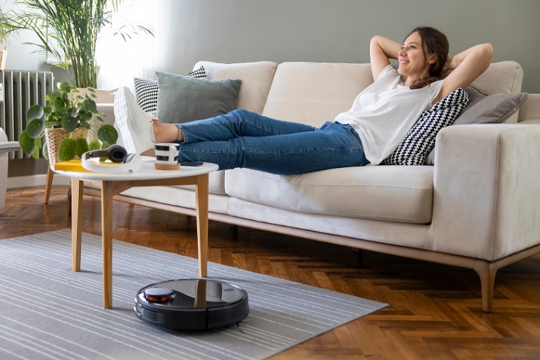 A person lying on a couch with her legs up on a vacuum cleaner

Description automatically generated